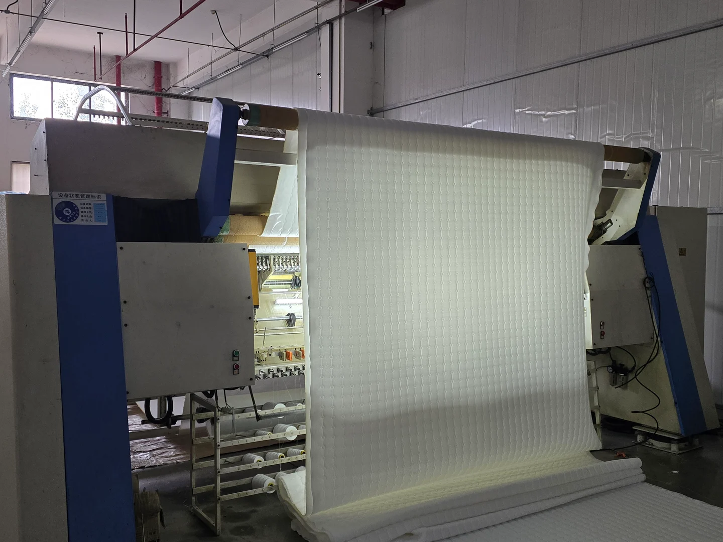Quilting equipment with a roll of white quilted bedding material