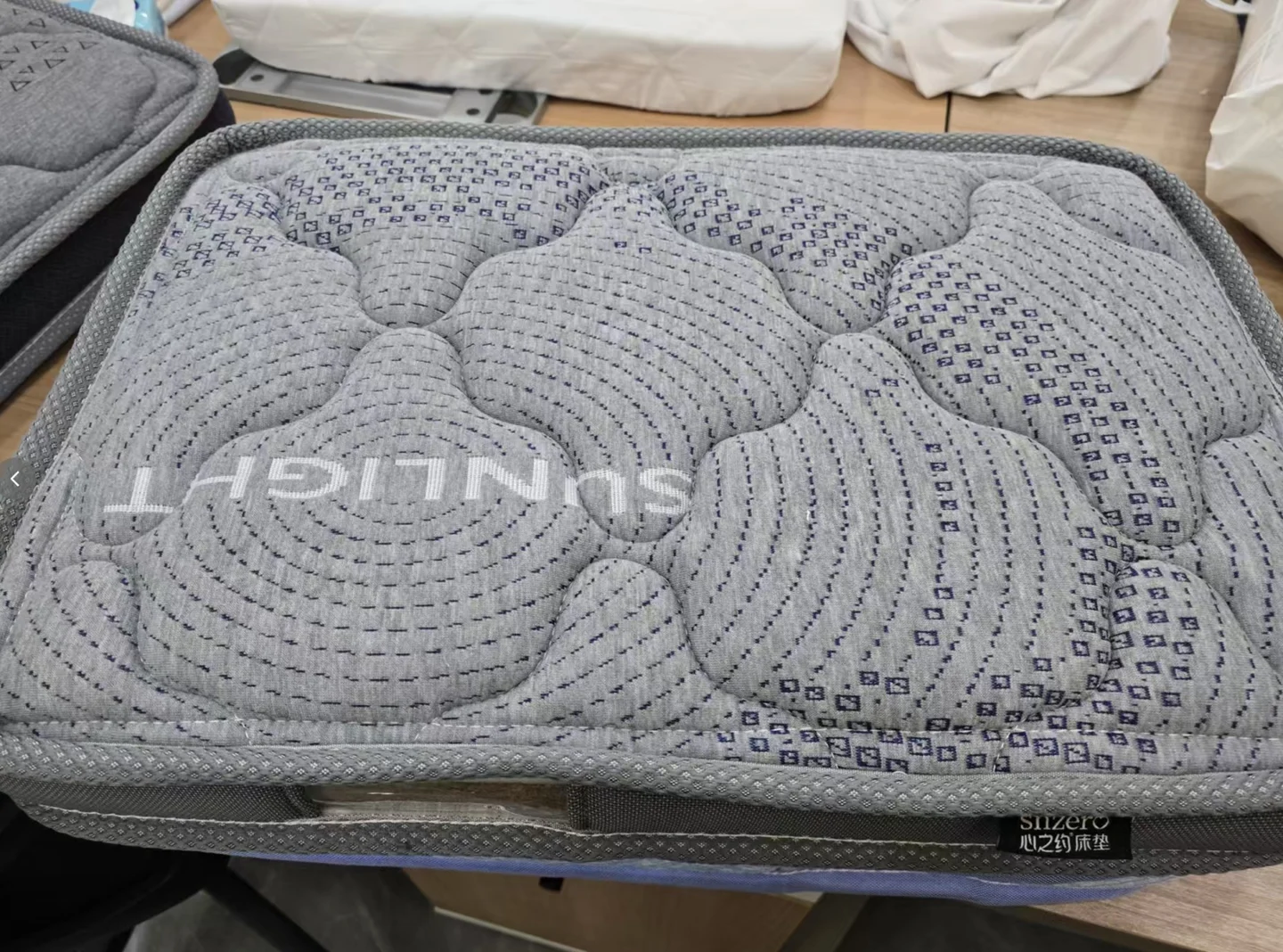 Real grey pet mattress sample with curved quilting, a rounded corner, a finished edge and side handle